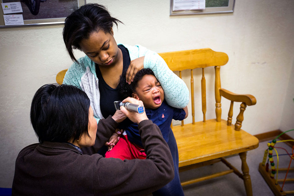 Mother holds her son while he has his temperature checked